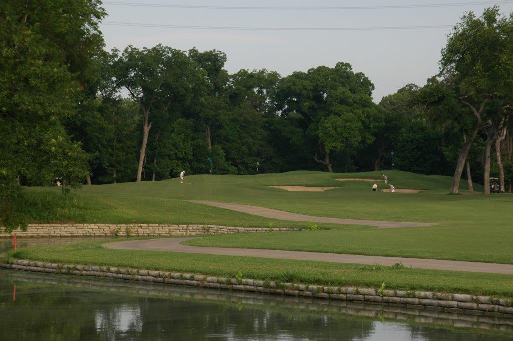 Golf course with a lake and a paved path,